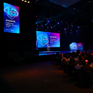 Palco de evento corporativo com design gráfico aplicado em LED walls, prismas decorativos e peça iluminada comemorativa dos 10 anos