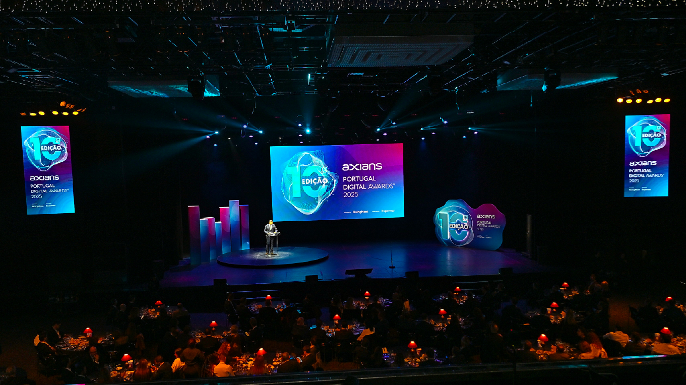 Palco de evento corporativo com design gráfico aplicado em LED walls, prismas decorativos e peça iluminada comemorativa dos 10 anos