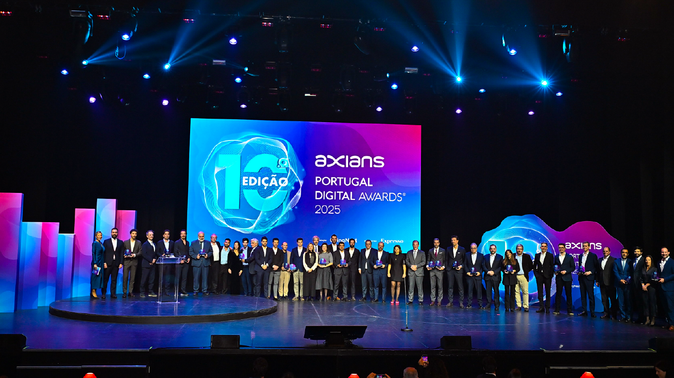 Cerimónia de prémios com vencedores em palco, LED wall com grafismo do evento, prismas decorativos e elemento iluminado com o número 10